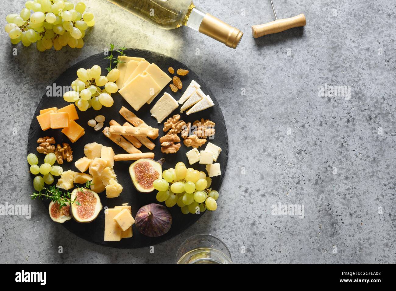 Plateau de fromages avec raisins, noix, figues sur fond de pierre grise. Vue de dessus. Hors-d'œuvre gastronomique festif pour les vacances. Banque D'Images