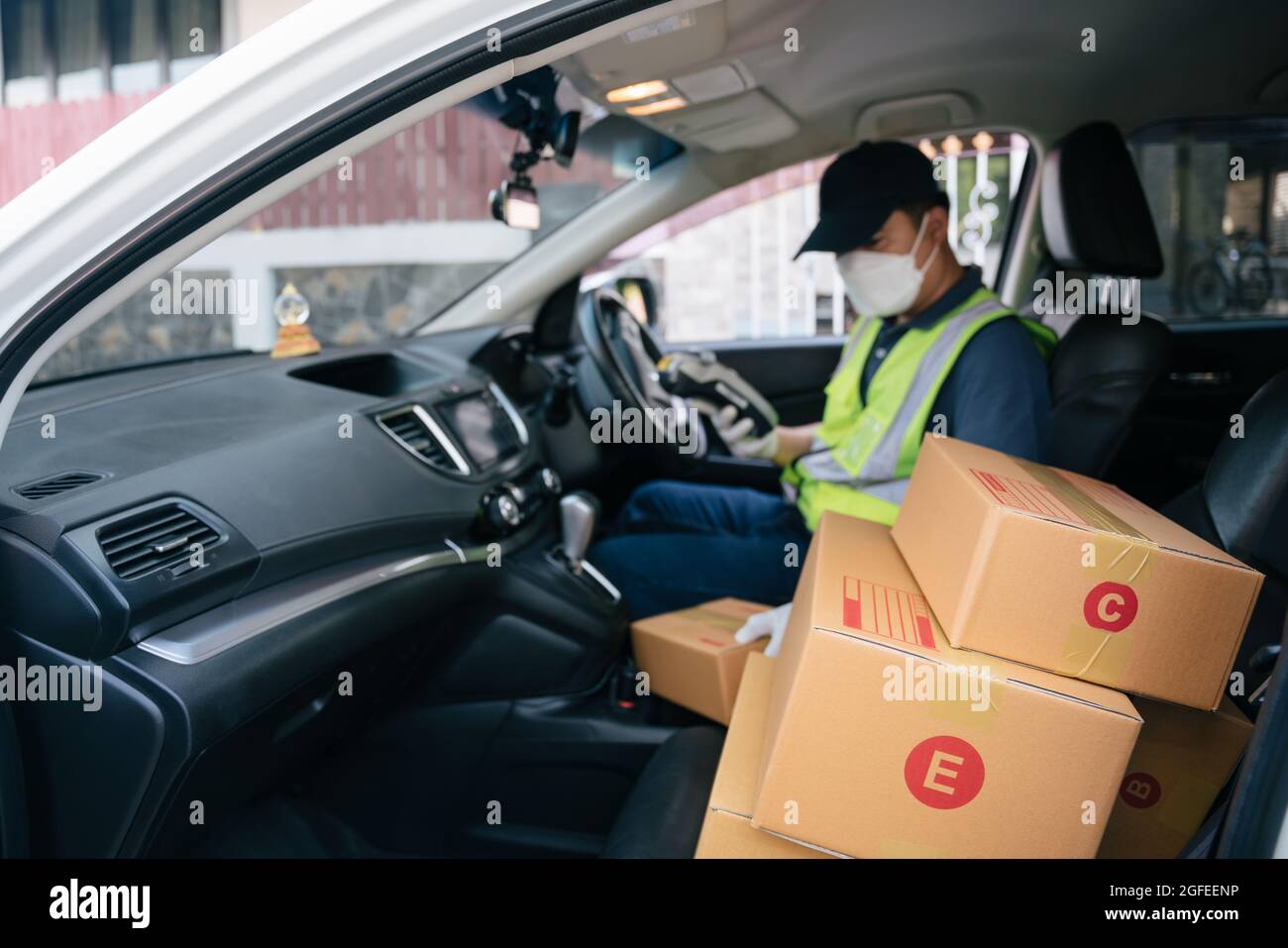 Sélectionnez Focus une boîte, UN liveur utilisant un lecteur de carte de crédit. Dans la camionnette avec colis à l'extérieur de l'entrepôt. Livraison Banque D'Images
