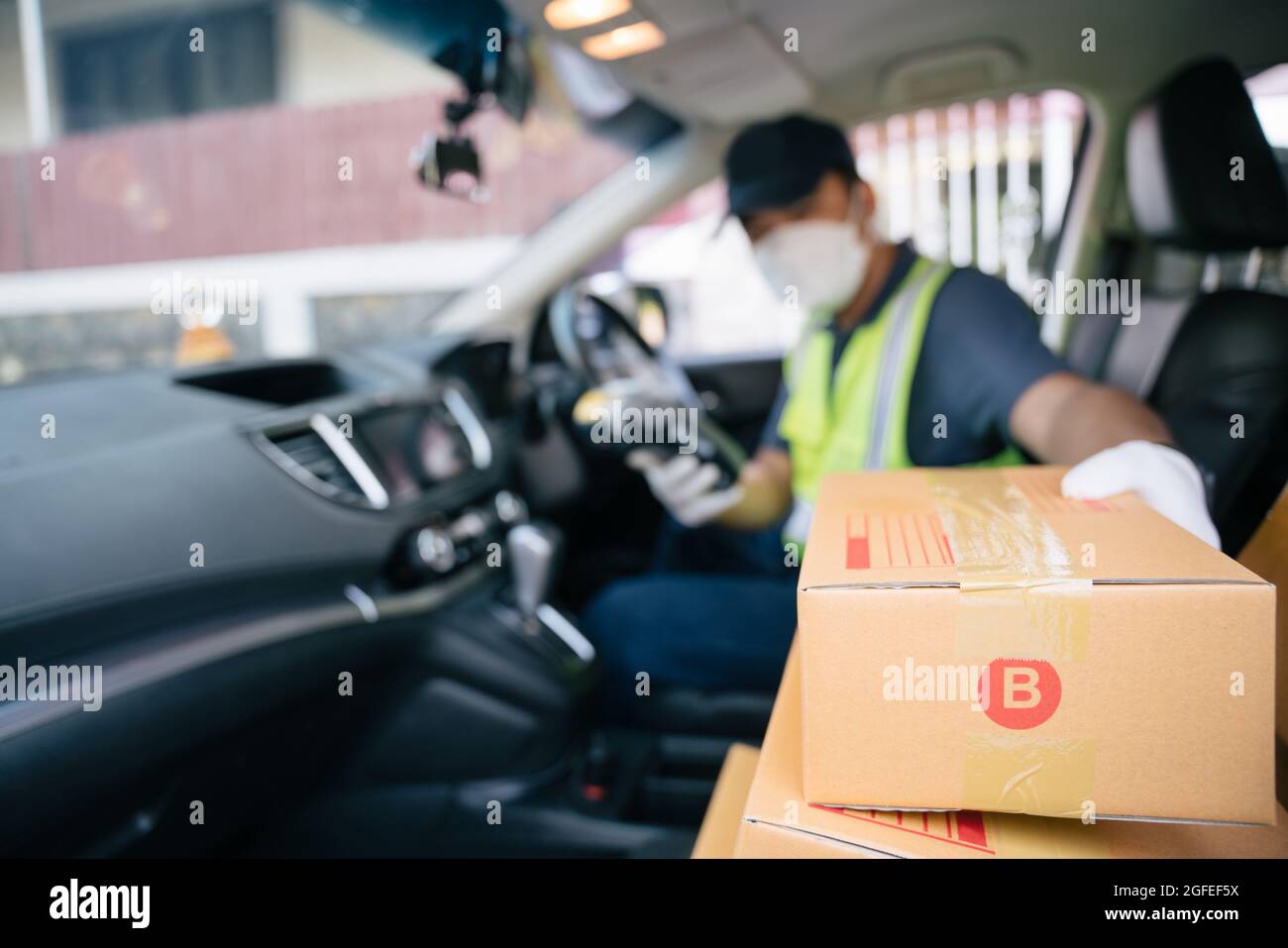 Un liveur prend une boîte dans la voiture d'un ami pour la livrer à un client, sélectionnez Focus a Box. Banque D'Images