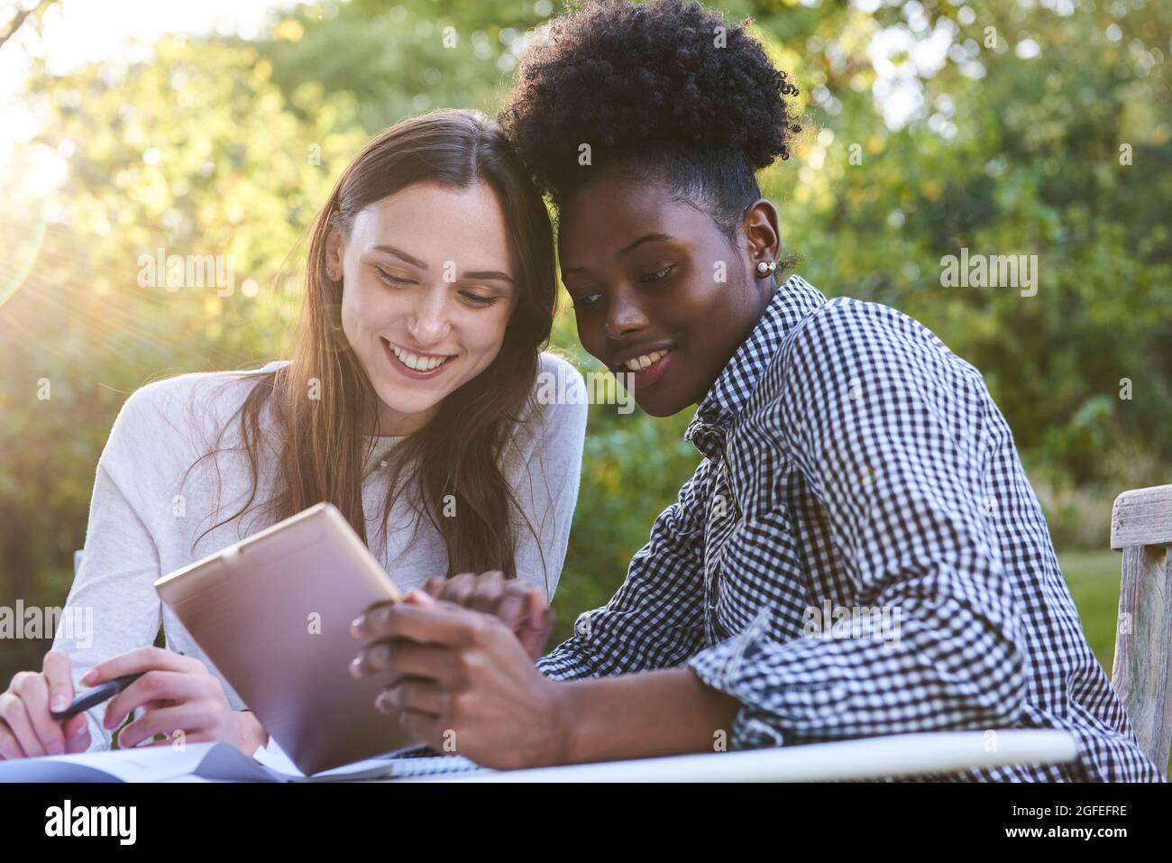 Des jeunes amis souriants utilisant une tablette numérique tout en étudiant dans le parc, Orgeval Banque D'Images