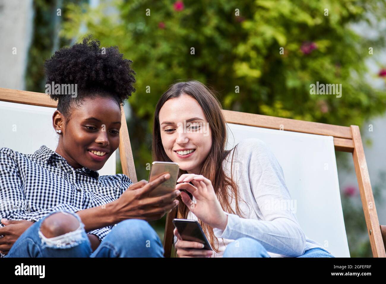 Des jeunes amis souriants à l'aide d'un smartphone dans le parc Banque D'Images