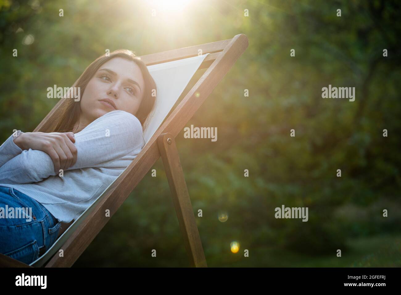 Jeune femme attentionnés avec les bras croisés s'inclinant sur la chaise Banque D'Images