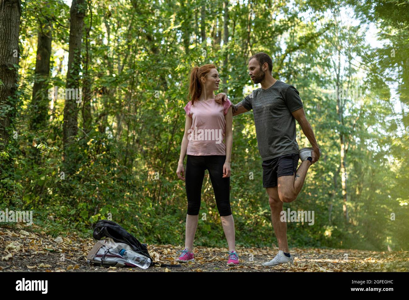 Jeune couple s'exerçant sur la piste en forêt Banque D'Images