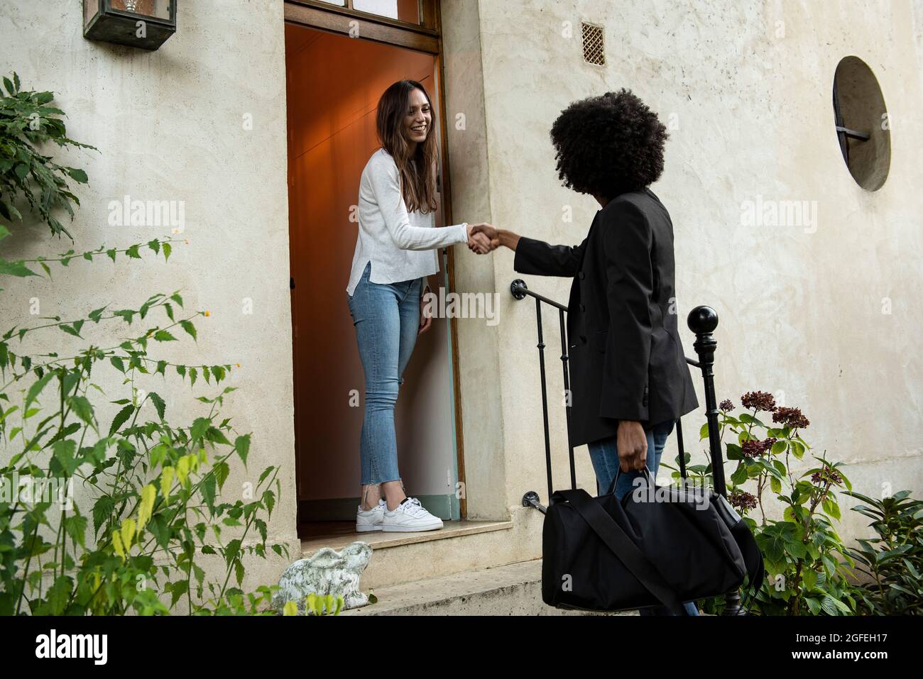 Des jeunes amies souriantes se branlant à la porte Banque D'Images