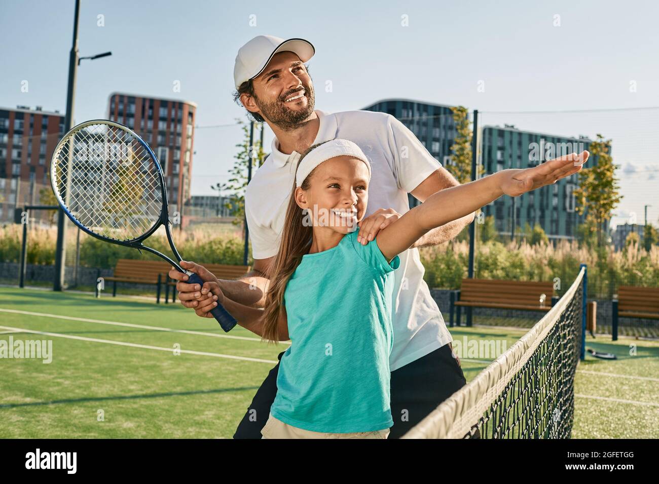 cours de tennis pour un enfant. entraîneur de tennis apprend à petite fille à jouer au tennis sur un court d'herbe Banque D'Images