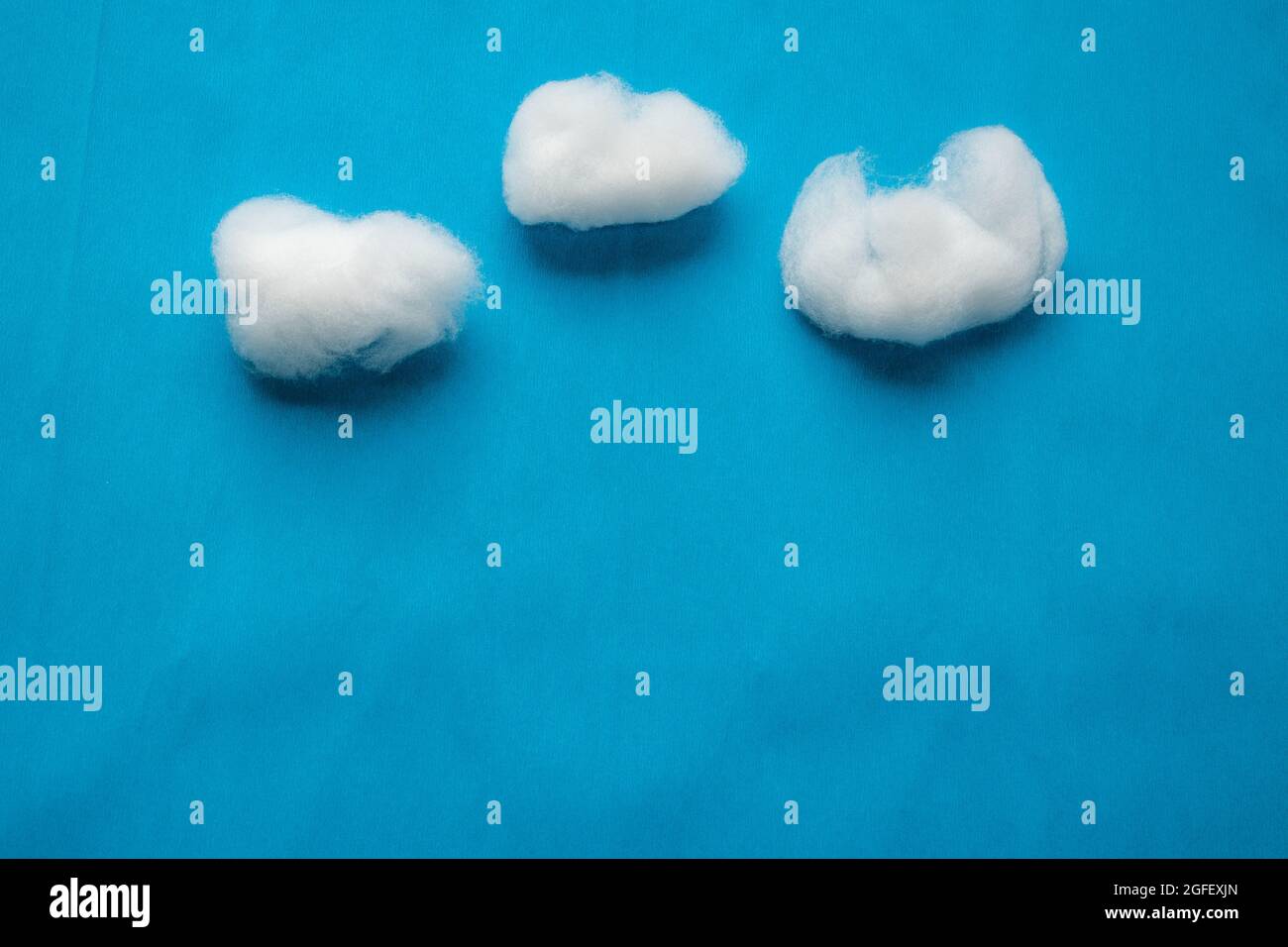 Reproduction des nuages sur ciel bleu avec de la laine de coton blanche sur fond de papier crêpé bleu. Banque D'Images