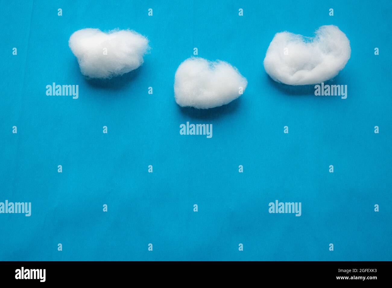 Reproduction des nuages sur ciel bleu avec de la laine de coton blanche sur fond de papier crêpé bleu. Banque D'Images