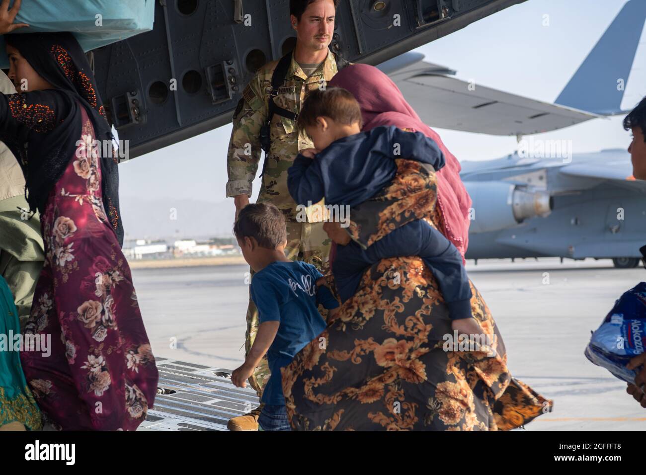 Kaboul, Afghanistan. 24 août 2021. Un aviateur de la Force aérienne des États-Unis avec le 816e Escadron de transport aérien expéditionnaire aide les réfugiés afghans à monter à bord d'un avion C-17 Globemaster III pour l'évacuation de l'aéroport international Hamid Karzaï pendant le refuge de l'opération alliés, le 24 août 2021 à Kaboul, en Afghanistan. Credit: Planetpix/Alamy Live News Banque D'Images