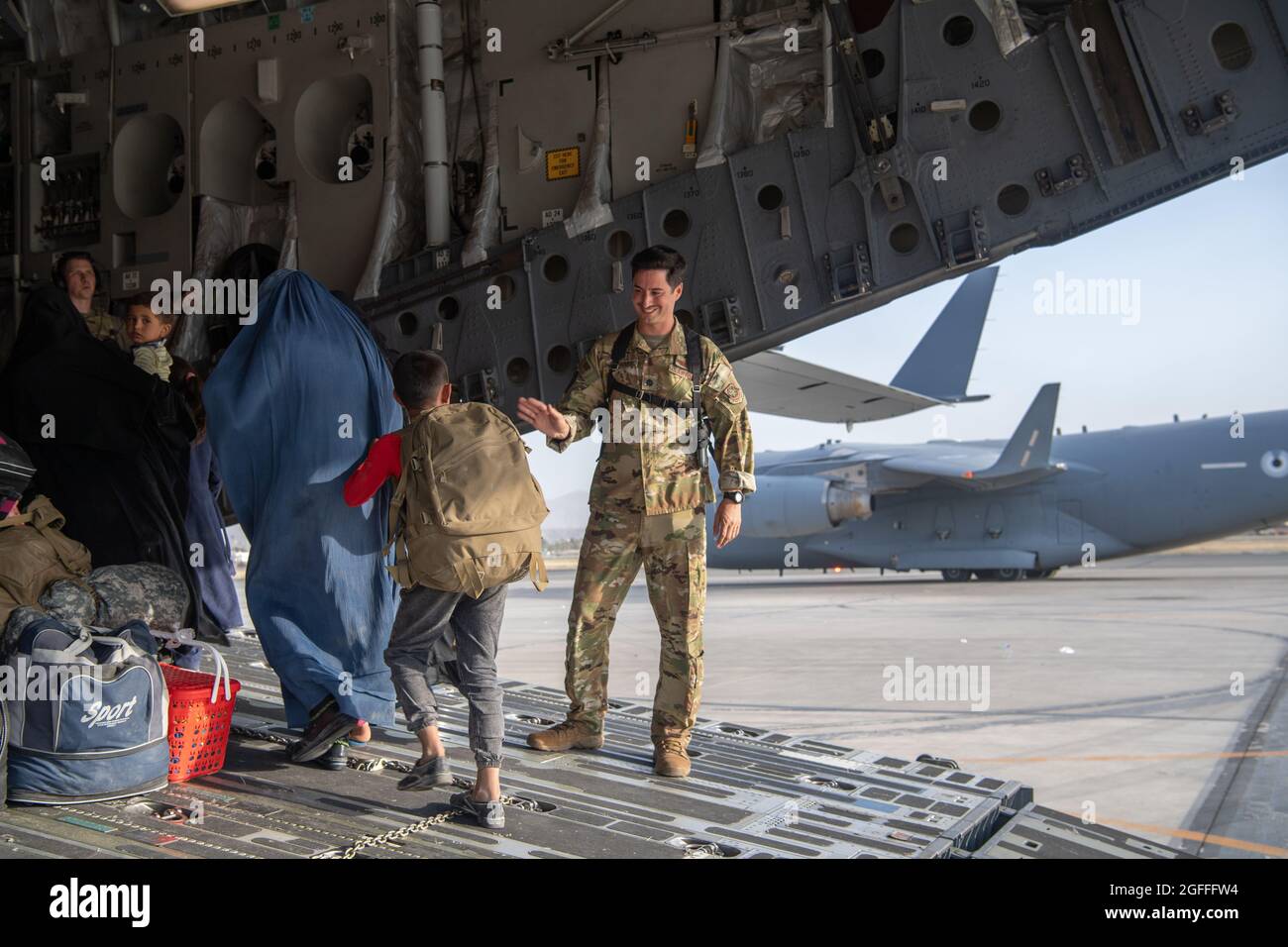 Kaboul, Afghanistan. 24 août 2021. Un aviateur de la Force aérienne des États-Unis avec le 816e Escadron de transport aérien expéditionnaire aide les réfugiés afghans à monter à bord d'un avion C-17 Globemaster III pour l'évacuation de l'aéroport international Hamid Karzaï pendant le refuge de l'opération alliés, le 24 août 2021 à Kaboul, en Afghanistan. Credit: Planetpix/Alamy Live News Banque D'Images