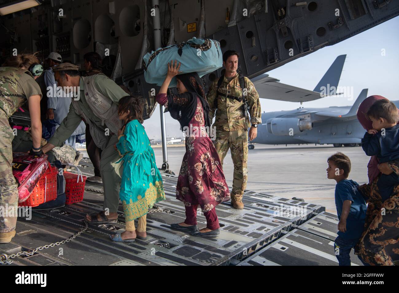 Kaboul, Afghanistan. 24 août 2021. Un aviateur de la Force aérienne des États-Unis avec le 816e Escadron de transport aérien expéditionnaire aide les réfugiés afghans à monter à bord d'un avion C-17 Globemaster III pour l'évacuation de l'aéroport international Hamid Karzaï pendant le refuge de l'opération alliés, le 24 août 2021 à Kaboul, en Afghanistan. Credit: Planetpix/Alamy Live News Banque D'Images