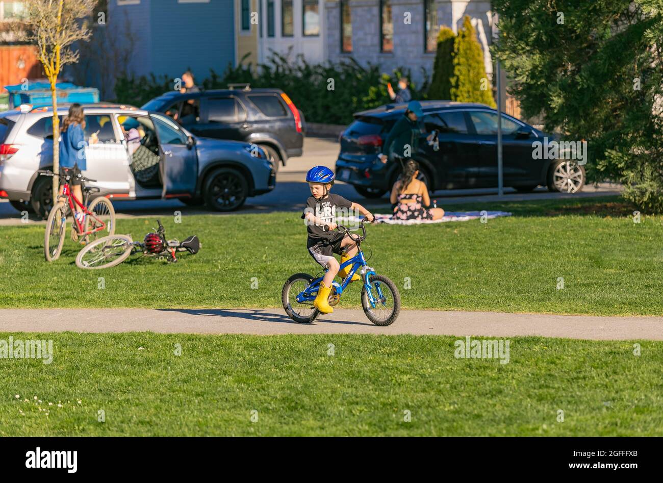 Petit garçon en casque bleu à vélo dans un parc de la ville. Vue sur la rue, photo de voyage, mise au point sélective. 18,2021 avril-Guildford, C.-B., Canada. Banque D'Images