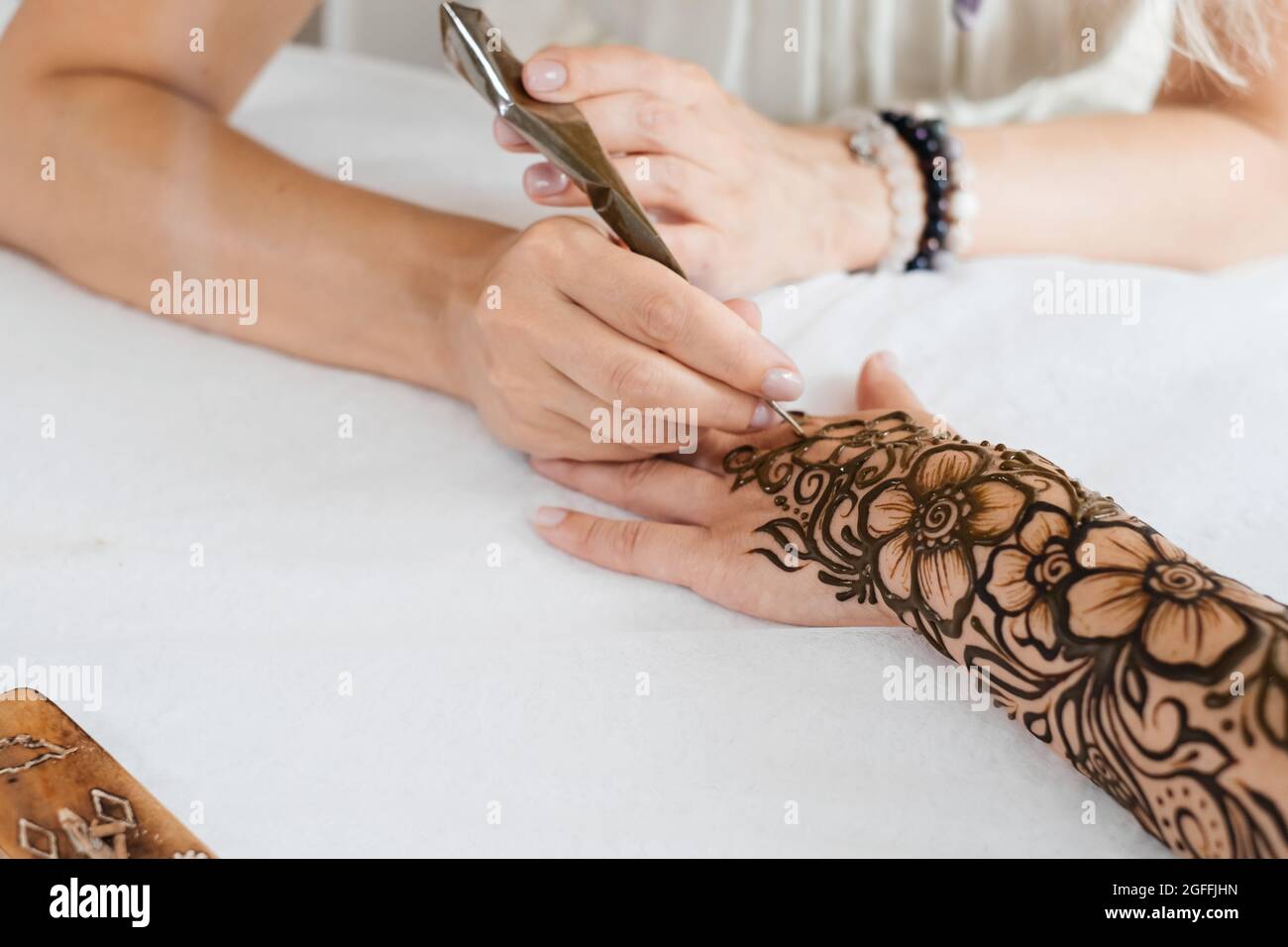 Vue de dessus art henné tatouage sur les mains des femmes. Maître artiste dessin arabe mehndi pour la mariée avant le mariage. Gros plan, vue de dessus. Motif fleuri. Cône Banque D'Images