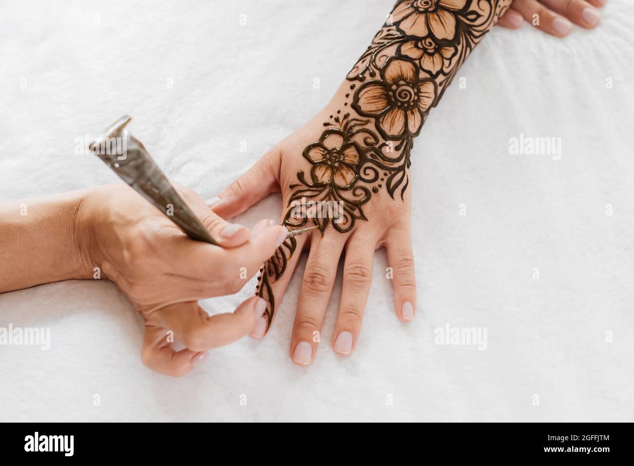 Vue de dessus art henné tatouage sur les mains des femmes. Maître artiste dessin arabe mehndi pour la mariée avant le mariage. Gros plan, vue de dessus. Motif fleuri. Cône Banque D'Images