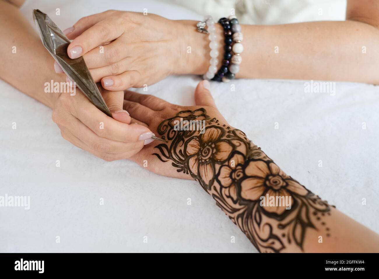 Vue de dessus art henné tatouage sur les mains des femmes. Maître artiste dessin arabe mehndi pour la mariée avant le mariage. Gros plan, vue de dessus. Motif fleuri. Cône Banque D'Images
