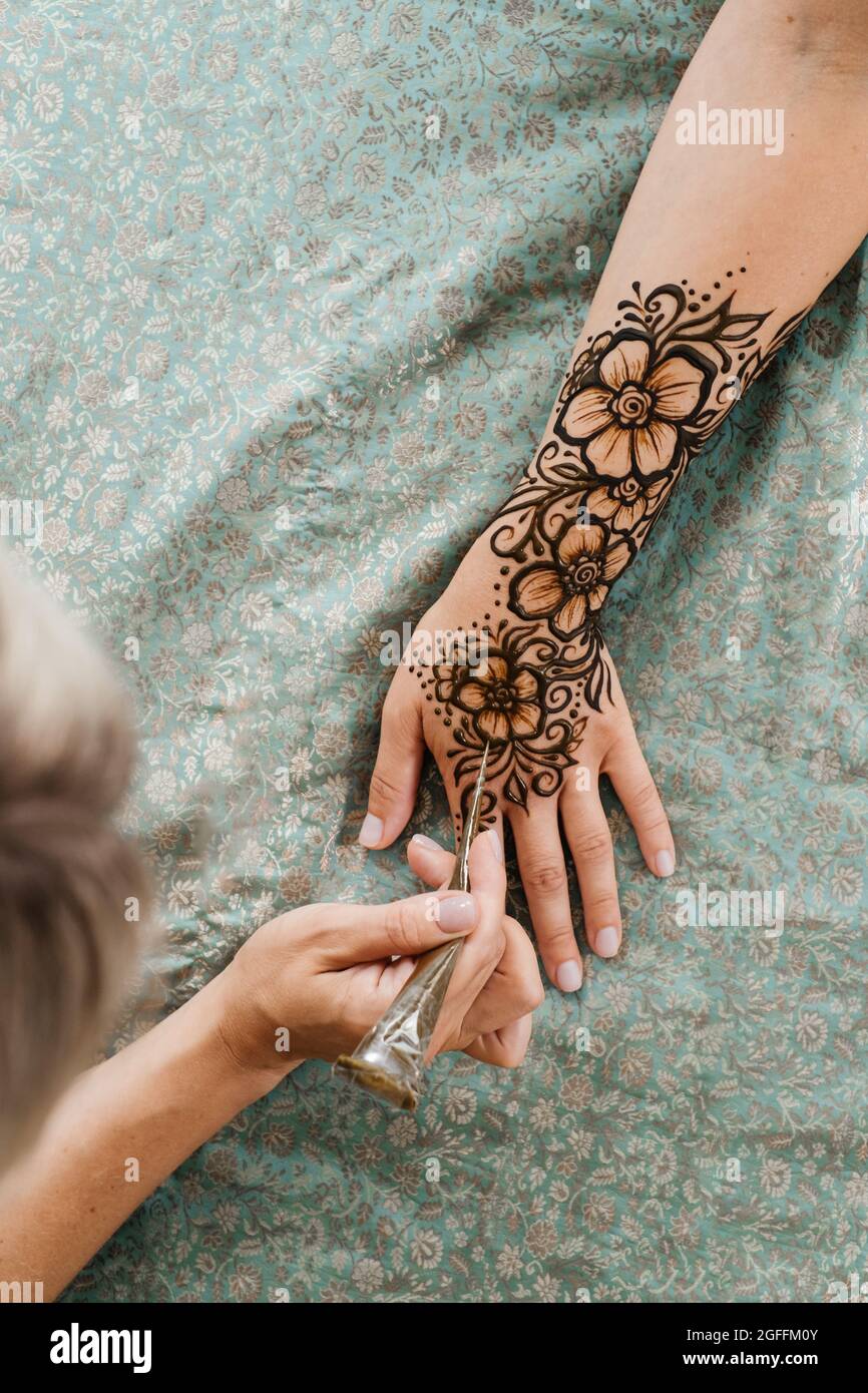 Vue de dessus art henné tatouage sur les mains des femmes. Maître artiste dessin arabe mehndi pour la mariée avant le mariage. Gros plan, vue de dessus. Motif fleuri. Cône Banque D'Images