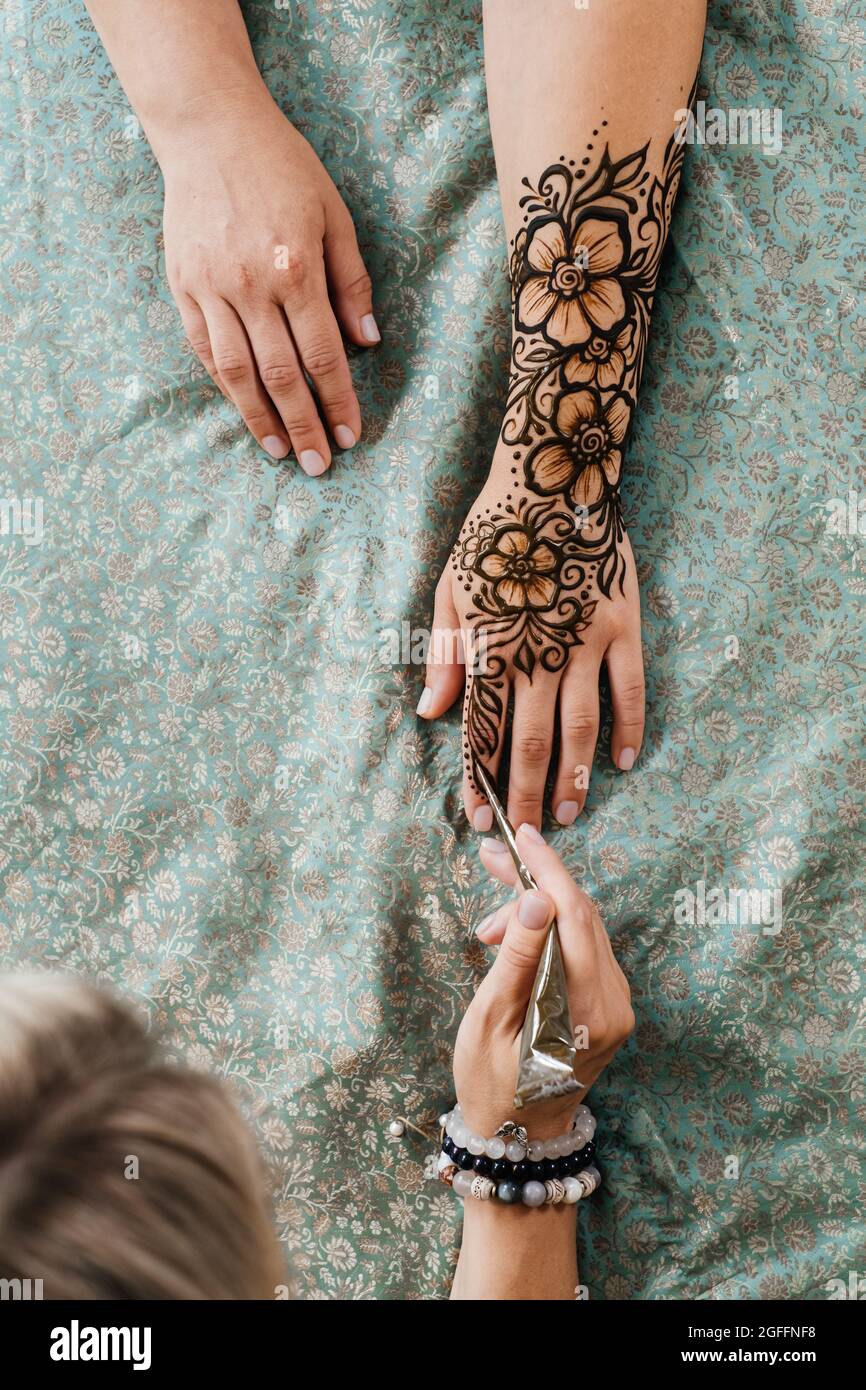 Vue de dessus art henné tatouage sur les mains des femmes. Maître artiste dessin arabe mehndi pour la mariée avant le mariage. Gros plan, vue de dessus. Motif fleuri. Cône Banque D'Images