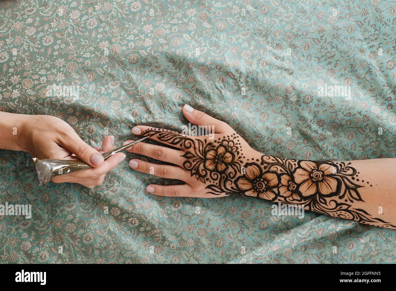 Vue de dessus art henné tatouage sur les mains des femmes. Maître artiste dessin arabe mehndi pour la mariée avant le mariage. Gros plan, vue de dessus. Motif fleuri. Cône Banque D'Images