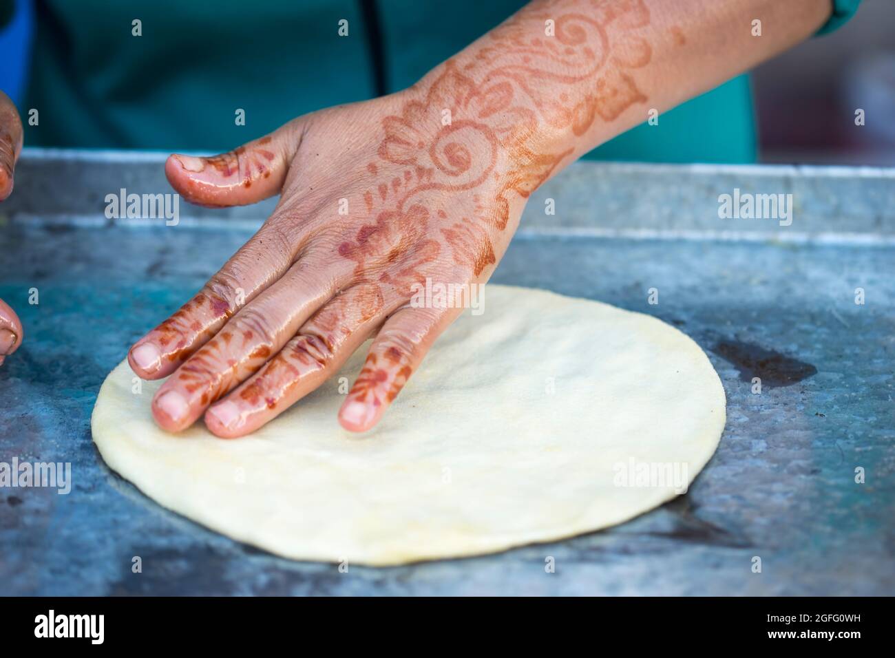 Femme avec tatouages au henné sur les mains préparant des crêpes.Msemin pâte à pain plat ronde préparée sur le gril, Marrakech, Maroc Essaouira, Maroc Banque D'Images