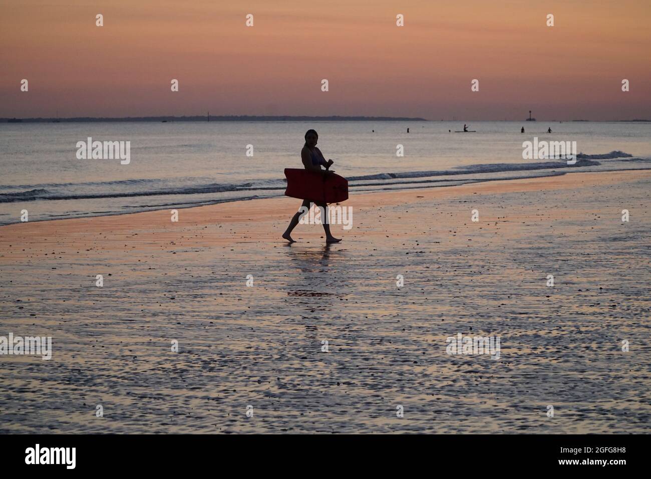 Météo au Royaume-Uni, 25 août 2021 : après une journée ensoleillée, un ciel clair offre de magnifiques couleurs dans le ciel, reflétées sur le sable humide, tandis que le soleil se couche sur le Solent. Les marcheurs pour chiens, les planchistes et les surfeurs peuvent profiter au maximum de la lumière persistante. Anna Watson/Alay Live News Banque D'Images