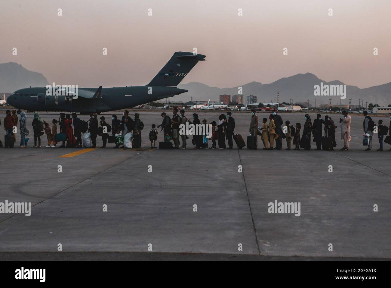 Les évacués attendent de monter à bord d'un Boeing C-17 Globemaster III lors d'une évacuation à l'aéroport international Hamid Karzaï, Kaboul, Afghanistan, le 23 août. Les membres du service américain aident le ministère d'État à effectuer une opération d'évacuation non combattantes (NEO) en Afghanistan. (É.-U. Photo du corps marin par Sgt. Isaiah Campbell) Banque D'Images