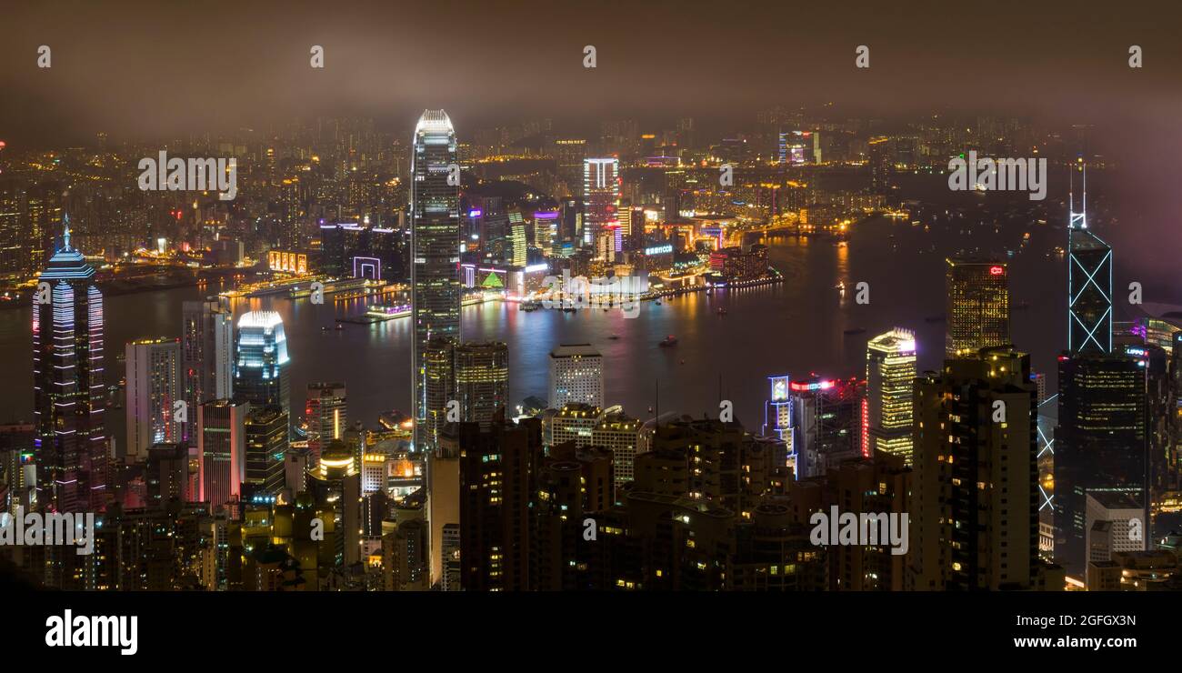 La montée du centre sur l'île de Hong Kong et Tsim Sha Tsui, Kowloon la nuit avec la fumée des feux d'artifice célébrant le nouvel an chinois Banque D'Images