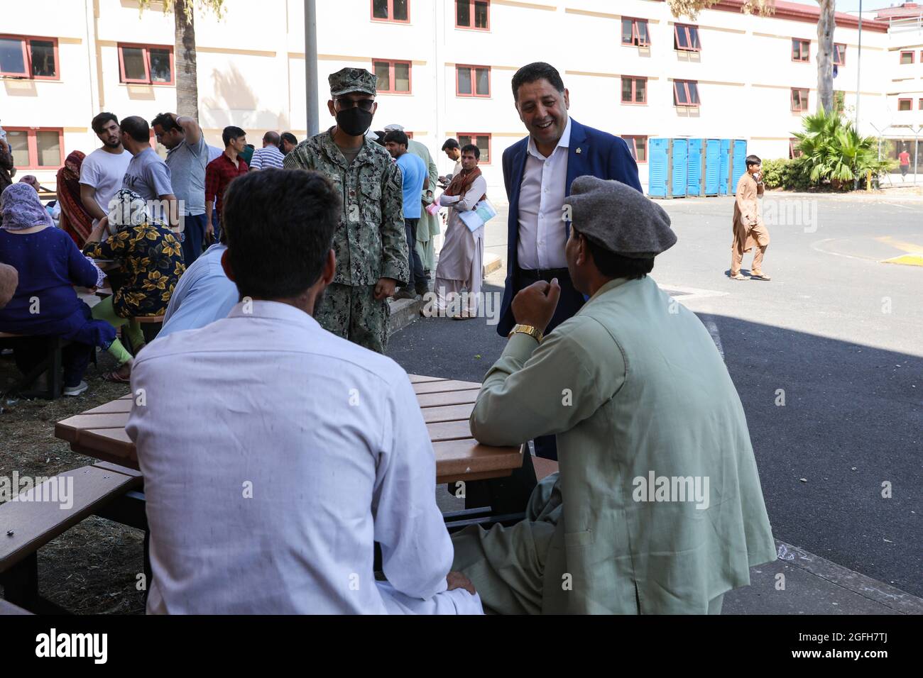 STATION NAVALE AÉRIENNE DE SIGONELLA, Italie (août 24, 2021) Kheit Abdelhafic, un imam de la communauté locale, de retour à droite, parle avec les évacués séjournant à la base aérienne navale de Sigonella, le 24 août 2021. NAS Sigonella appuie actuellement la mission du ministère de la Défense visant à faciliter le départ et le déplacement en toute sécurité des citoyens américains, des bénéficiaires de visas d'immigration spéciaux et des populations afghanes vulnérables en provenance d'Afghanistan. (É.-U. Photo de la marine par Claire DuBois, spécialiste des communications de masse, 2e classe) Banque D'Images
