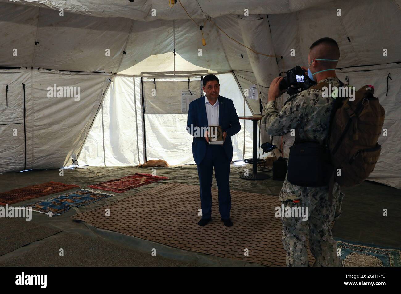 STATION NAVALE AÉRIENNE DE SIGONELLA, Italie (août 24, 2021) Kheit Abdelhafic, un imam de la communauté locale, visite une tente de prière mise en place pour les évacués musulmans et explique son importance pour le Spécialiste de la communication de masse de première classe Caine Storino à la base aérienne navale de Sigonella, le 24 août 2021. NAS Sigonella appuie actuellement la mission du ministère de la Défense visant à faciliter le départ et le déplacement en toute sécurité des citoyens américains, des bénéficiaires de visas d'immigration spéciaux et des populations afghanes vulnérables en provenance d'Afghanistan. (É.-U. Photo de la marine par Claire DuBois, spécialiste des communications de masse, 2e classe) Banque D'Images