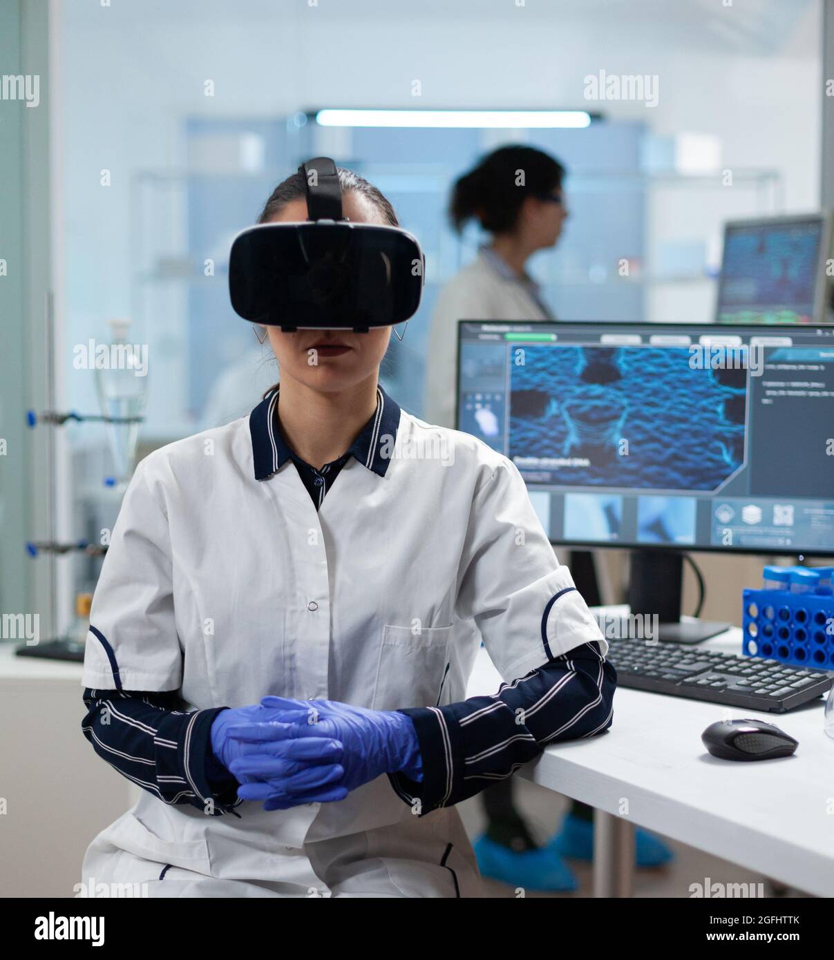 Biologiste scientifique femme portant un casque de réalité virtuelle analysant l'expertise des vaccins médicaux pendant une expérience biotechnologique travaillant dans un laboratoire hospitalier de microbiologie. Enquête scientifique Banque D'Images