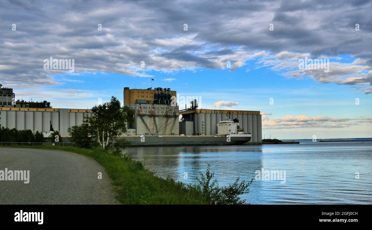 Un élévateur de grain centenaire se trouve sur le lac supérieur à Thunder Bay, Ontario, Canada, alors qu'un cargo arrive pour ramasser le grain le jour du printemps. Banque D'Images