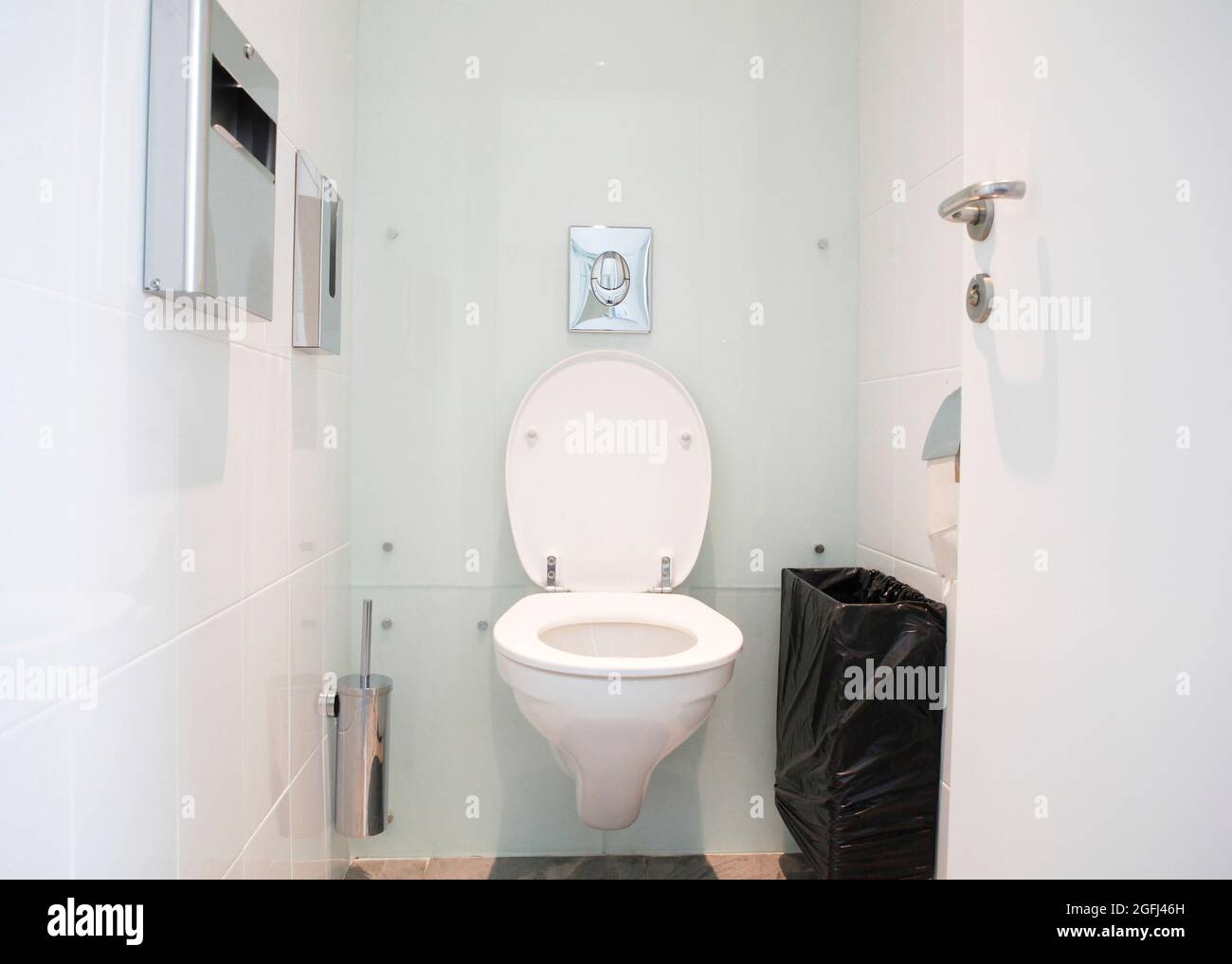 Placard à eau blanc, salle de bains de restaurant, petite salle de toilettes avec un mur fixé au mur, cuvette de toilettes en céramique, brosse de toilettes, corbeille à déchets, papier toilette Banque D'Images