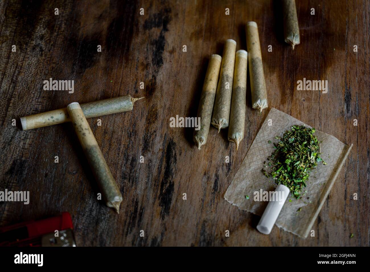 Gros plan sur les articulations roulées avec du cannabis vert, du briquet et du papier. Banque D'Images