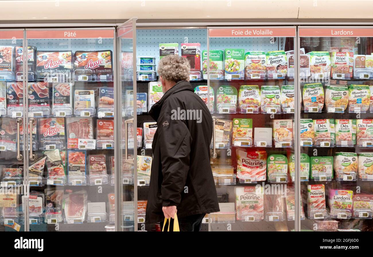 Supermarché Super U: Un homme au milieu du rayon des aliments frais, emballé sous vide de viande froide cuite, protége, foie de volaille, dés de bacon Banque D'Images