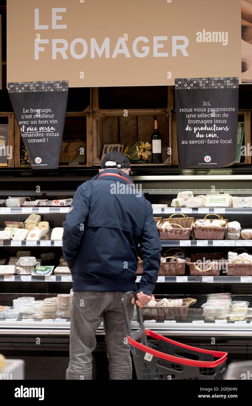 Supermarché Super U : quelqu'un devant le fromage dans le comptoir de fromage du rayon des produits laitiers Banque D'Images