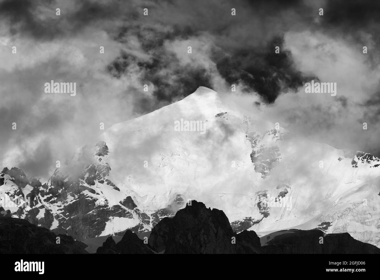Montagnes noires et blanches hautes enneigées avec glacier, rochers et ciel avec brouillard sombre avant la tempête. Montagnes du Caucase. Géorgie, région de Svanetia, Mont Tetnu Banque D'Images