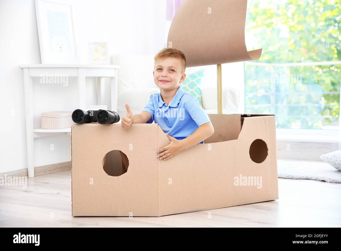 Petit garçon jouant avec carton navire à l'intérieur Photo Stock - Alamy