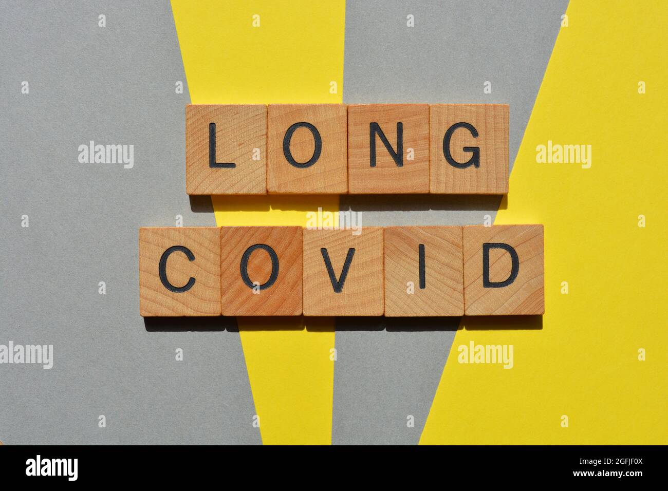 Long Covid, mots en lettres de l'alphabet en bois isolées sur fond jaune et gris Banque D'Images