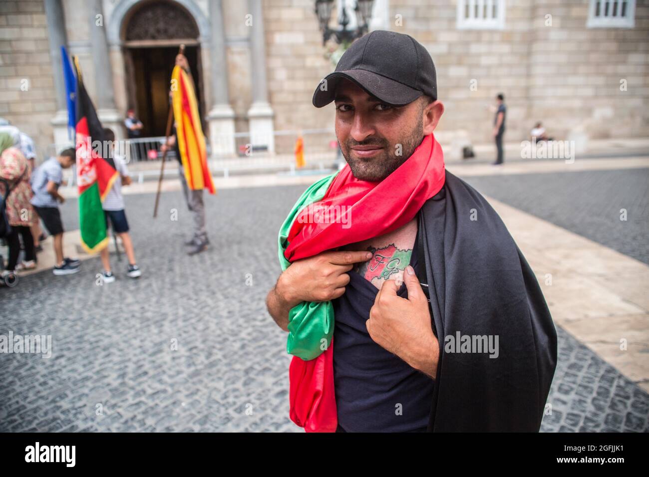 Barcelone, Catalogne, Espagne. 25 août 2021. Un manifestant couvert d'un drapeau afghan est vu montrant un tatouage de la carte afghane avec les couleurs du drapeau afghan devant la Generalitat de Catalunya.l'association afghane de Barcelone a démontré devant la Generalitat de Catalogne pour demander au gouvernement la protection et Évacuation de leurs familles qui sont restées en Afghanistan. (Image de crédit : © Thiago Prudencio/DAX via ZUMA Press Wire) Banque D'Images