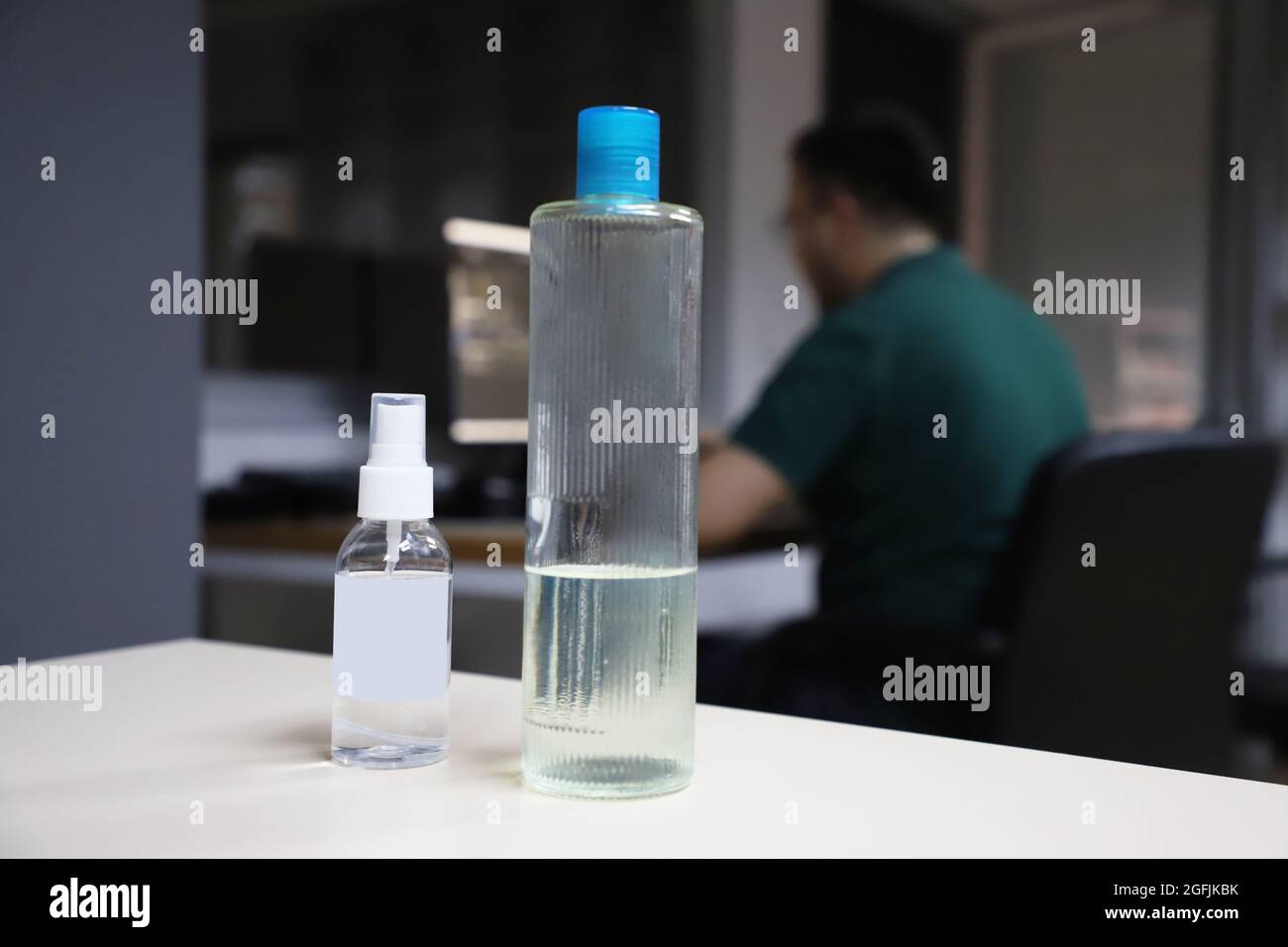 flacon de désinfectant et de cologne. un homme travaillant dans le bureau en arrière-plan. Banque D'Images