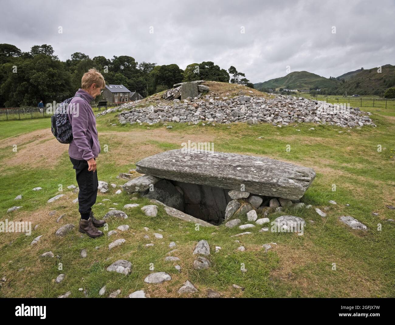 Dame à côté d'un Cairn à Kilmartin Glen regardant un Ciste de sépulture Banque D'Images