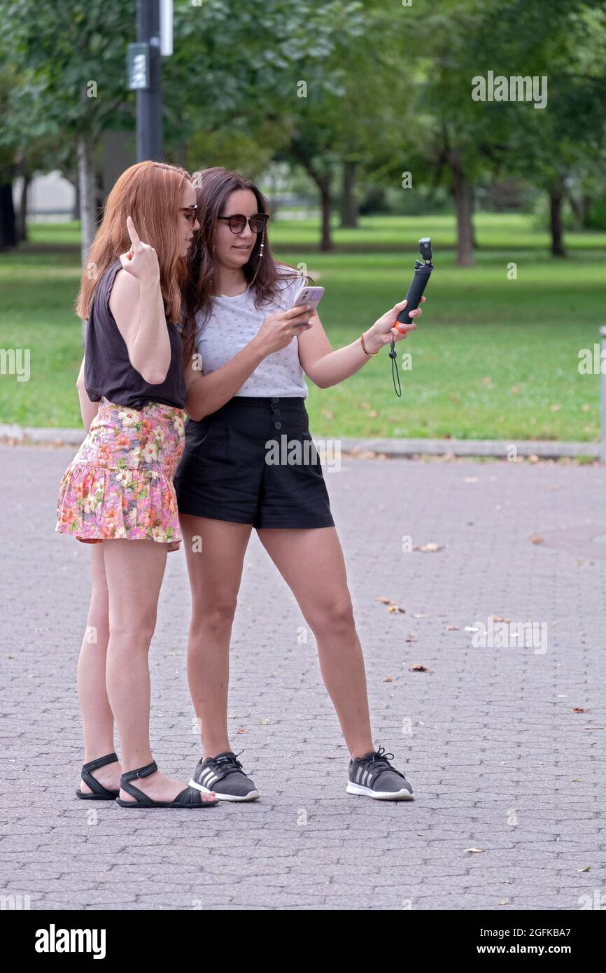 Les femmes attirantes en jupes courtes prennent un double selfie - avec un  téléphone cellulaire et avec un GoPro. Dans un parc à Queens, New York  Photo Stock - Alamy