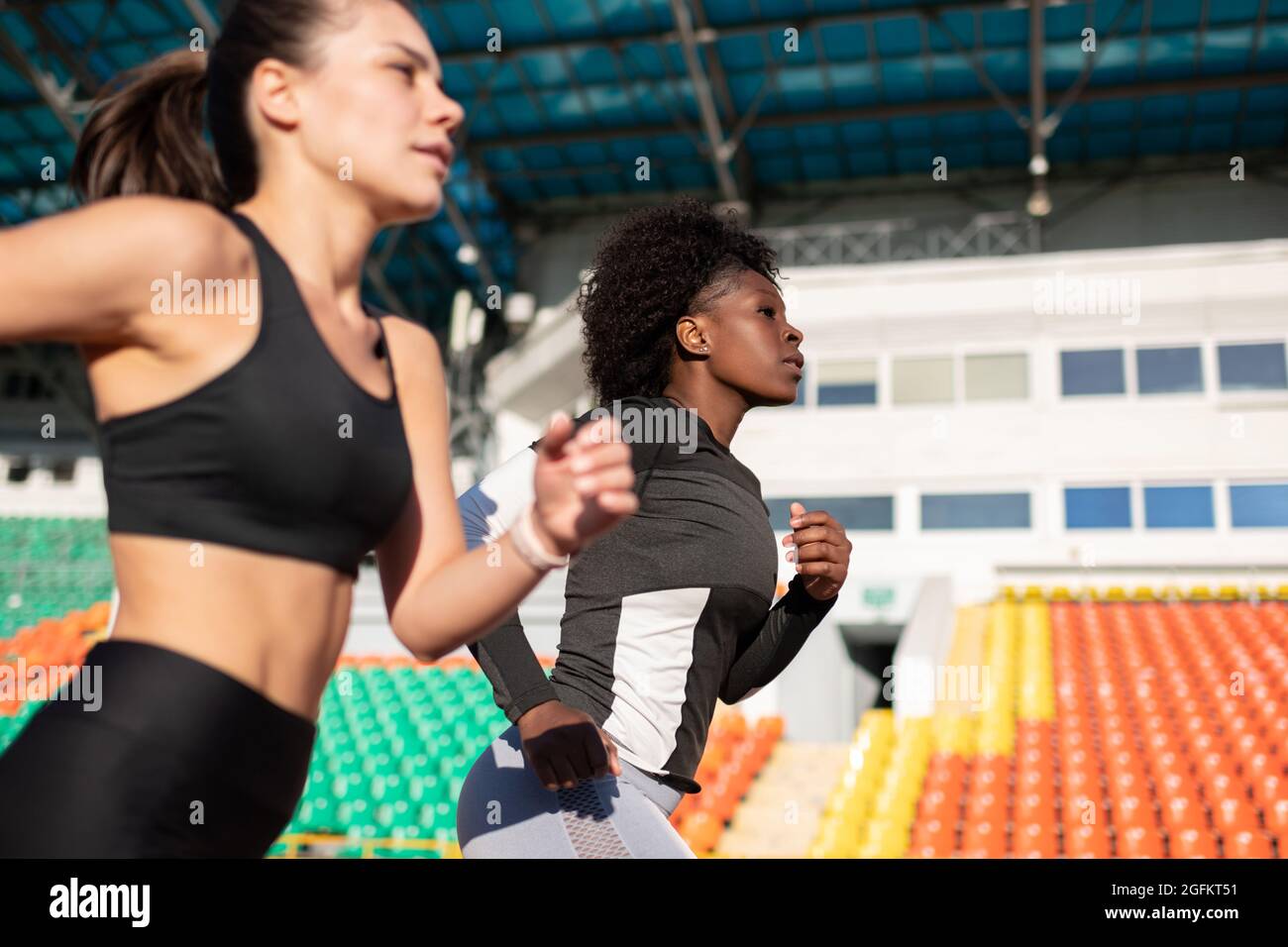 Divers sportswomen courant rapidement pendant l'entraînement sur piste et sur le terrain dans le stade Banque D'Images