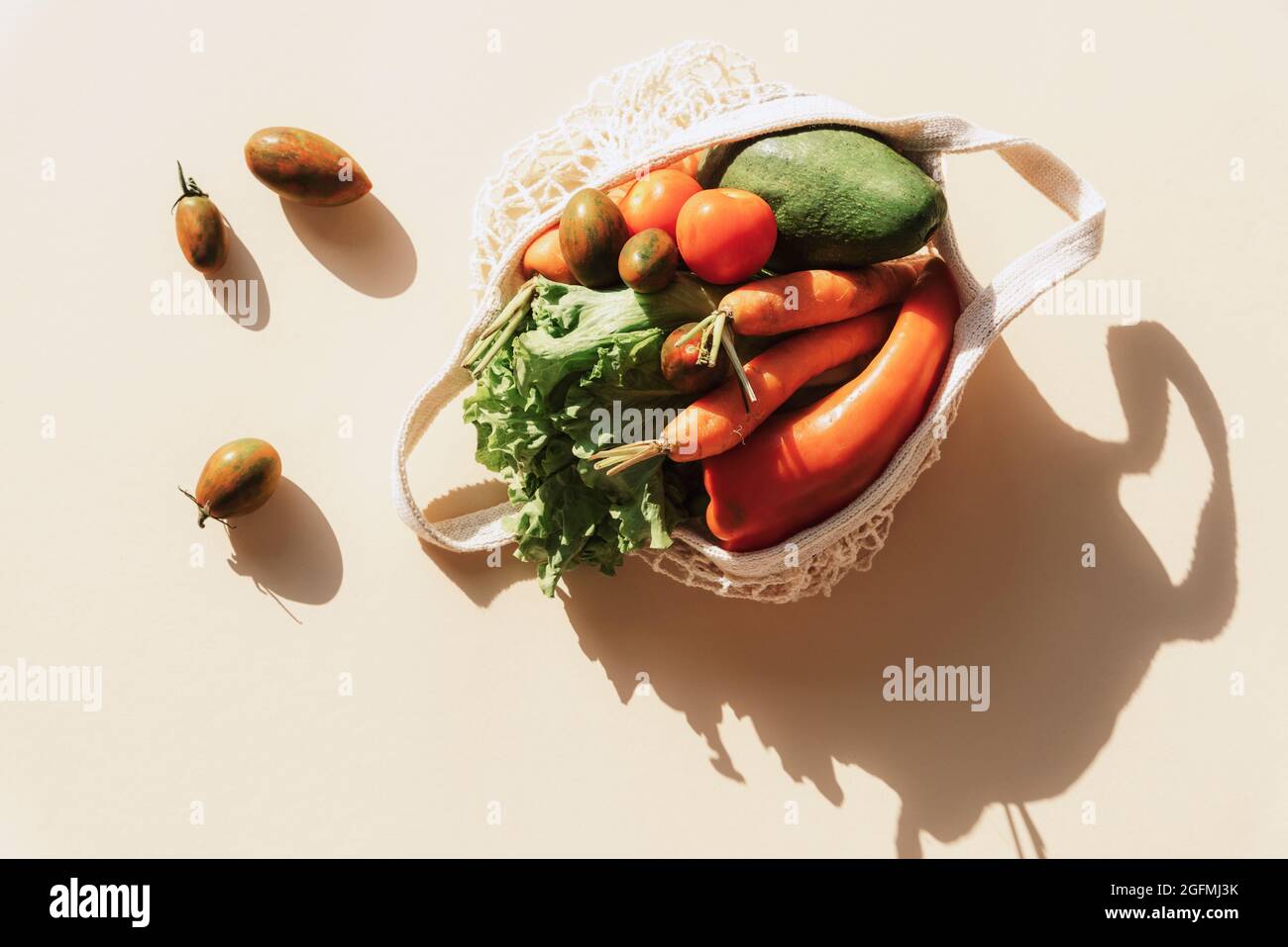 Légumes frais mûrs dans un sac à ficelle. Concept zéro déchet, nourriture saine. Ombres nettes, vue de dessus, pose à plat. Banque D'Images