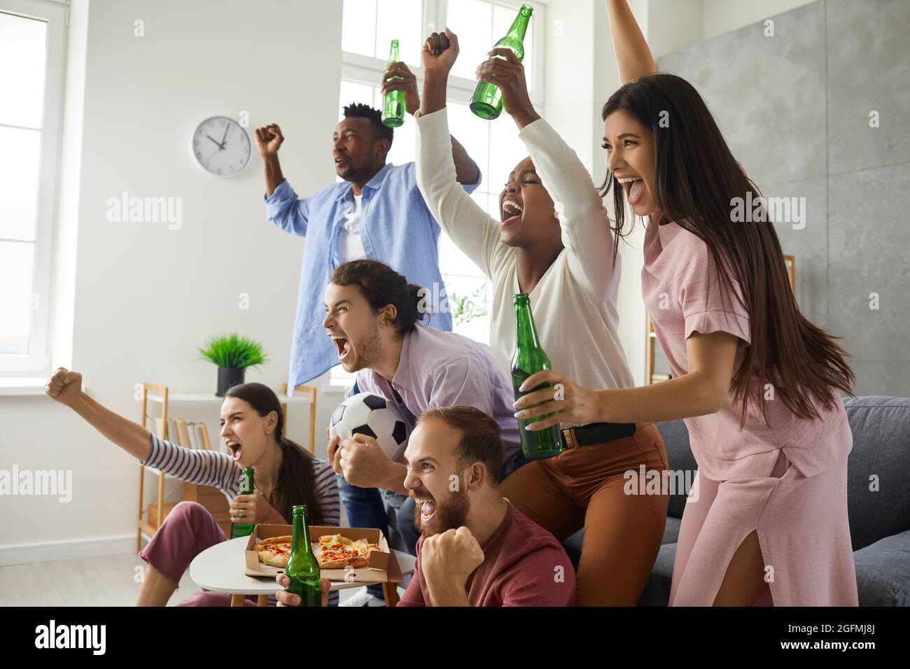 Groupe d'amis regardant le football à la télévision, criant et soutenant l'équipe préférée Banque D'Images