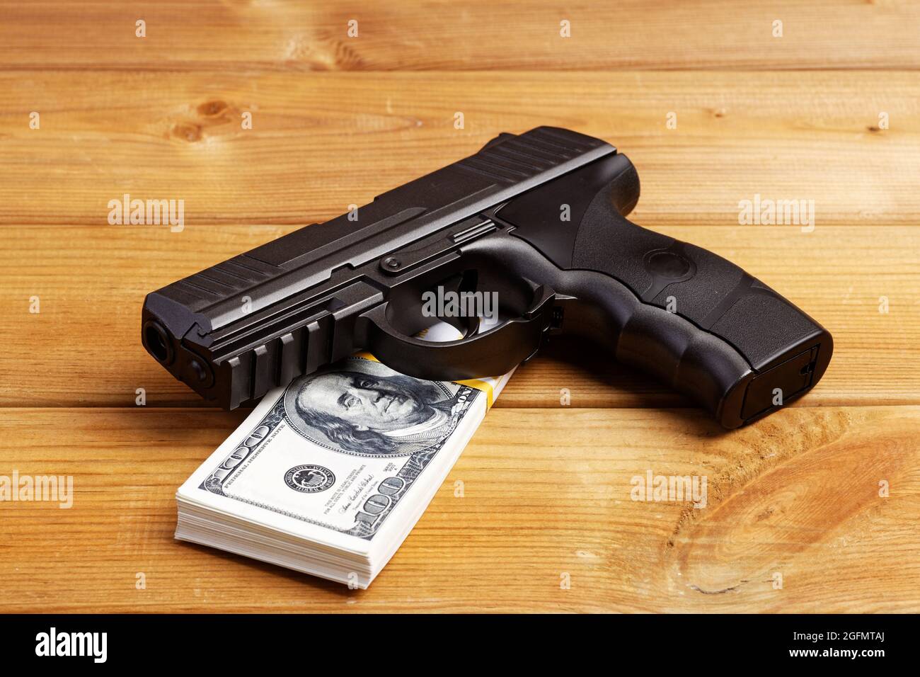 Pistolet à main noir et billets en dollars sur table en bois. Banque D'Images Pistolet à main noir et billets en dollars sur table en bois. Banque D'Images