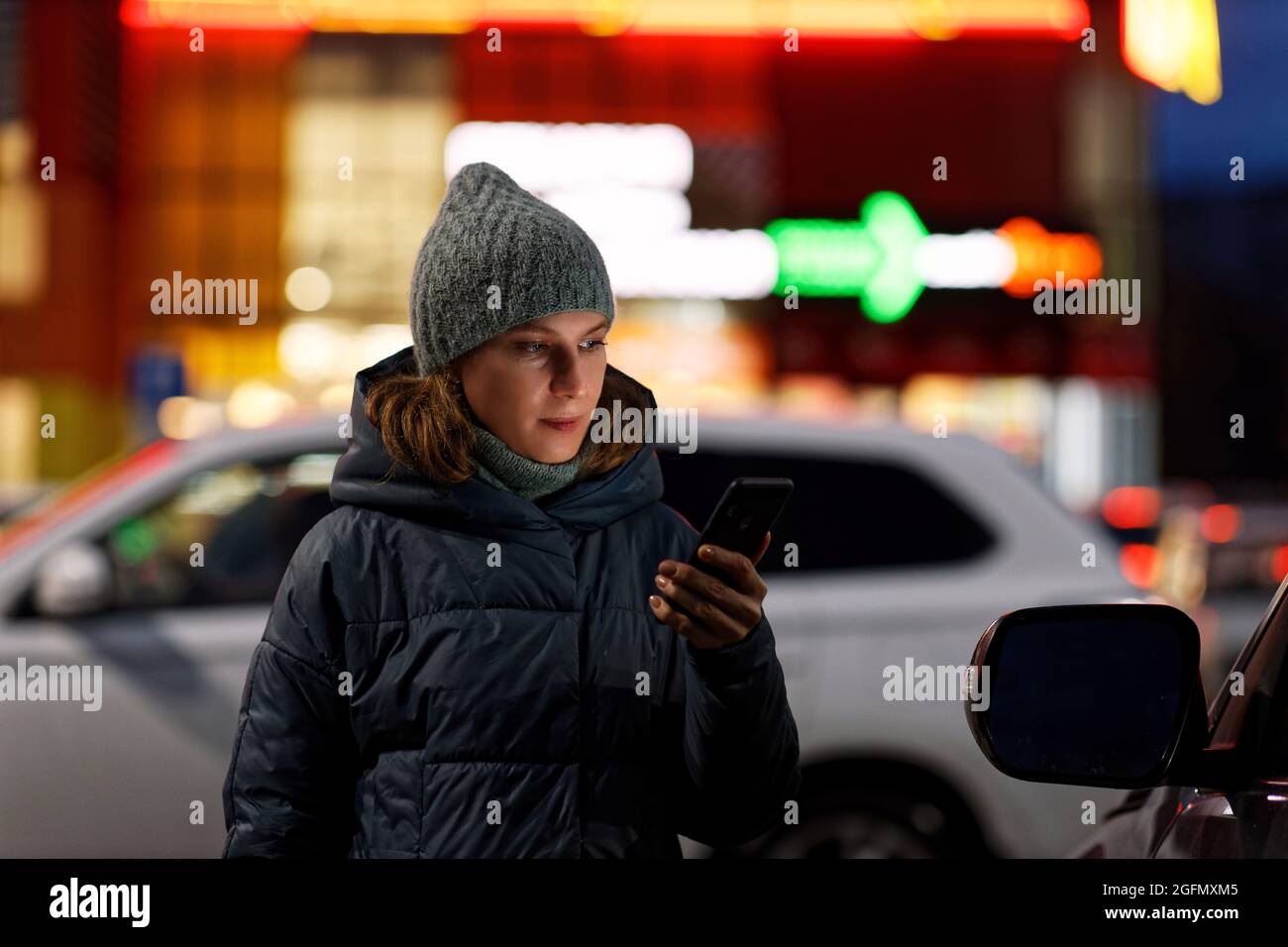 Portrait extérieur d'une jeune femme utilisant son smartphone en ville nocturne. Mise au point peu profonde. Banque D'Images Portrait extérieur d'une jeune femme utilisant son smartphone en ville nocturne. Mise au point peu profonde. Banque D'Images