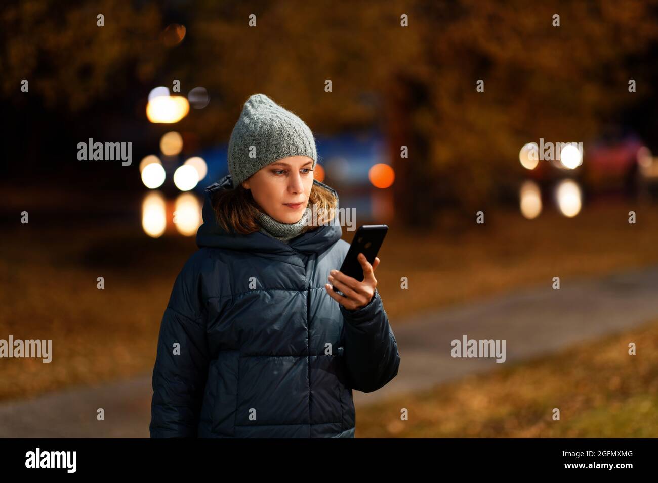 Portrait extérieur d'une jeune femme utilisant son smartphone en ville nocturne. Mise au point peu profonde. Banque D'Images Portrait extérieur d'une jeune femme utilisant son smartphone en ville nocturne. Mise au point peu profonde. Banque D'Images