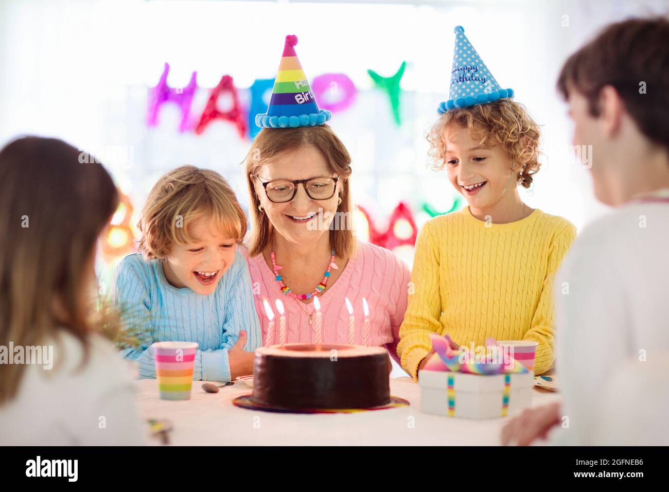 Fete D Anniversaire Pour Enfants Bougies Soufflantes Pour Enfants Sur Le Gateau Et Les Cadeaux D Ouverture Celebration Sur Le Theme De L Arc En Ciel Famille Celebrant A La Maison Garcon Et Fille Photo Stock