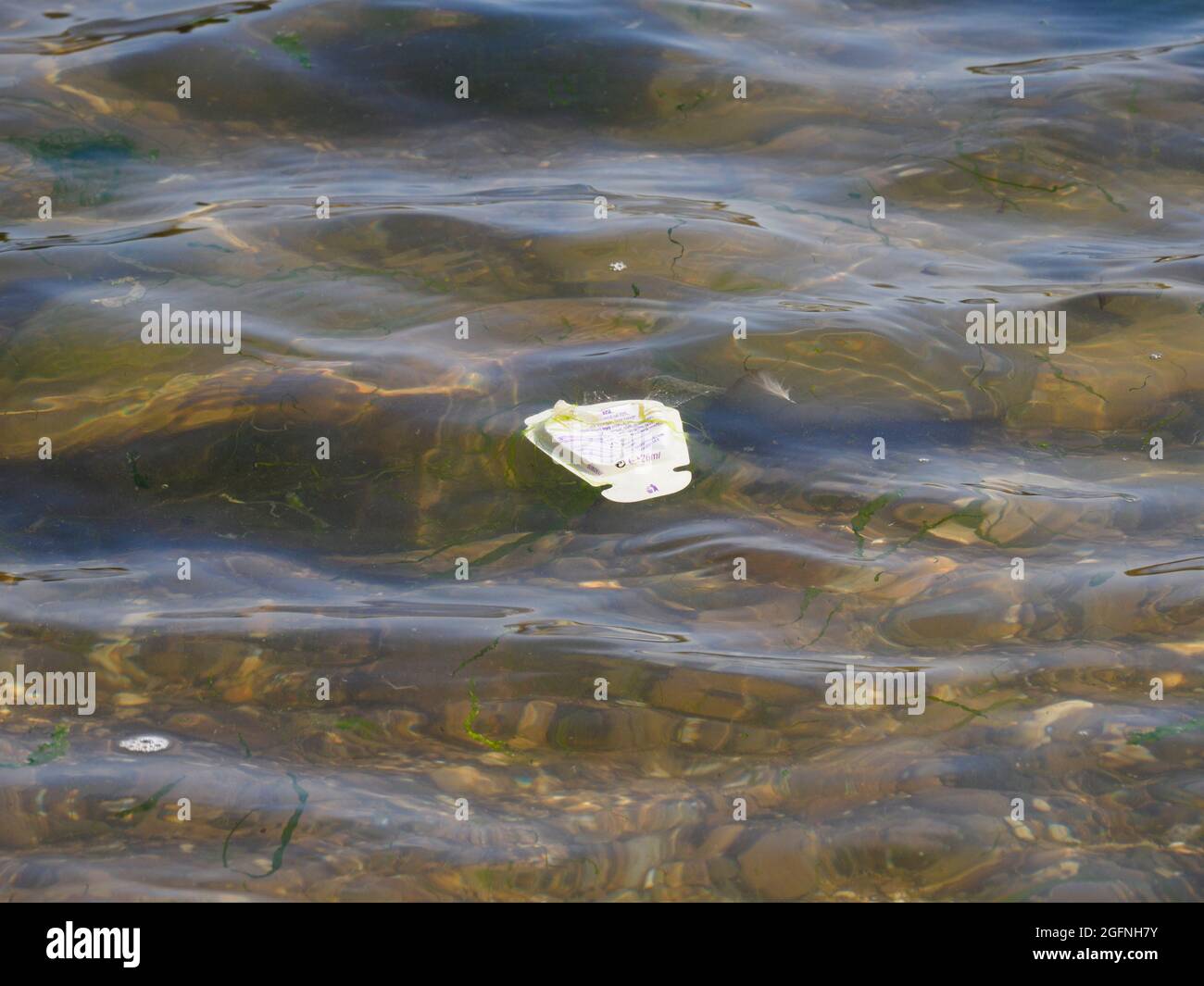 Emballage alimentaire en plastique flottant dans la mer, Bude, Cornwall, Royaume-Uni Banque D'Images