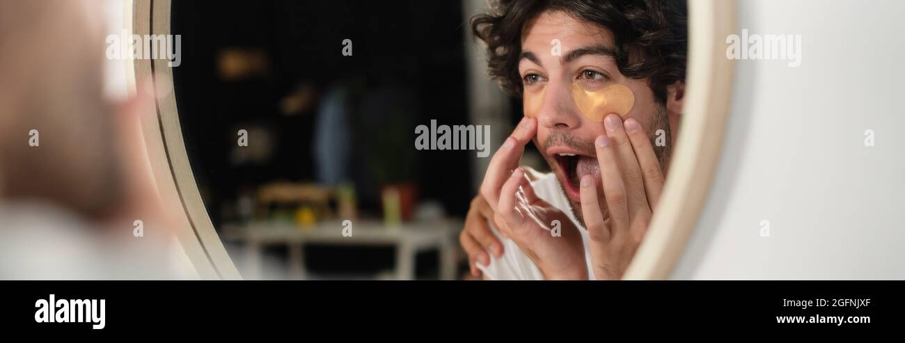 homme homosexuel appliquant des cellules oculaires et regardant le miroir, la bannière Banque D'Images