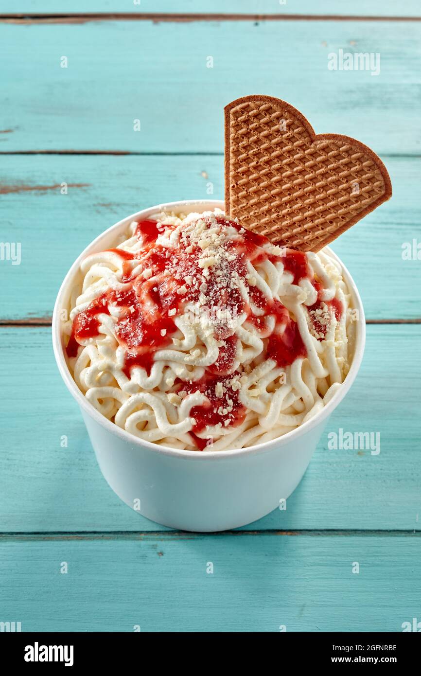 Nouilles spaghetti à la crème glacée à la vanille allemande tendance et  sauce aux baies ou tomate servies dans une baignoire avec un biscuit en  galette, vue de haut en bas sur